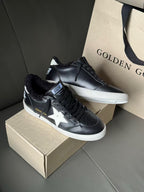 Black low-top sneakers with white star side logo and perforated toe details