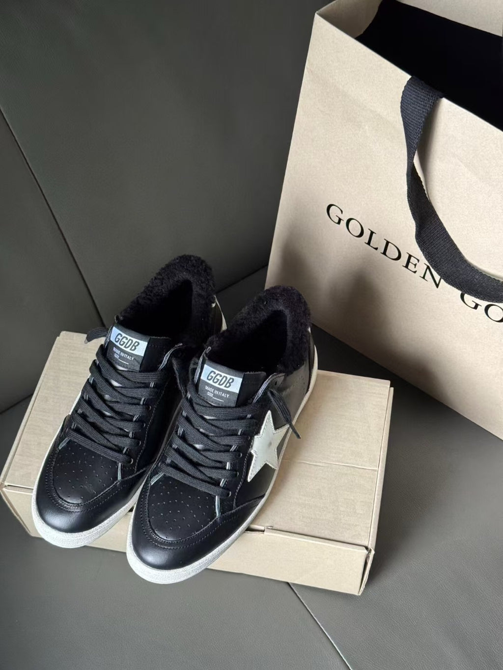 Two black low-top sneakers with lace-up fronts, white star logos, and knit lining