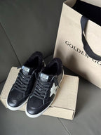 Two black low-top sneakers with lace-up fronts, white star logos, and knit lining