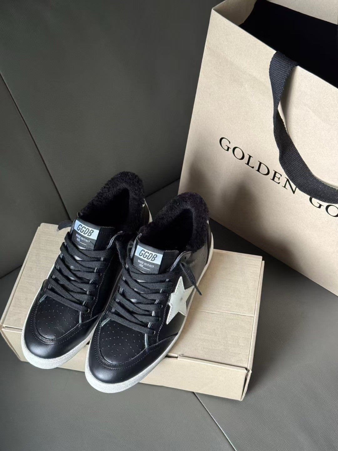 Two black low-top sneakers with lace-up fronts, white star logos, and knit lining