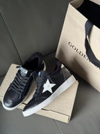 Black low-top sneakers with white star patch and white rubber outsole