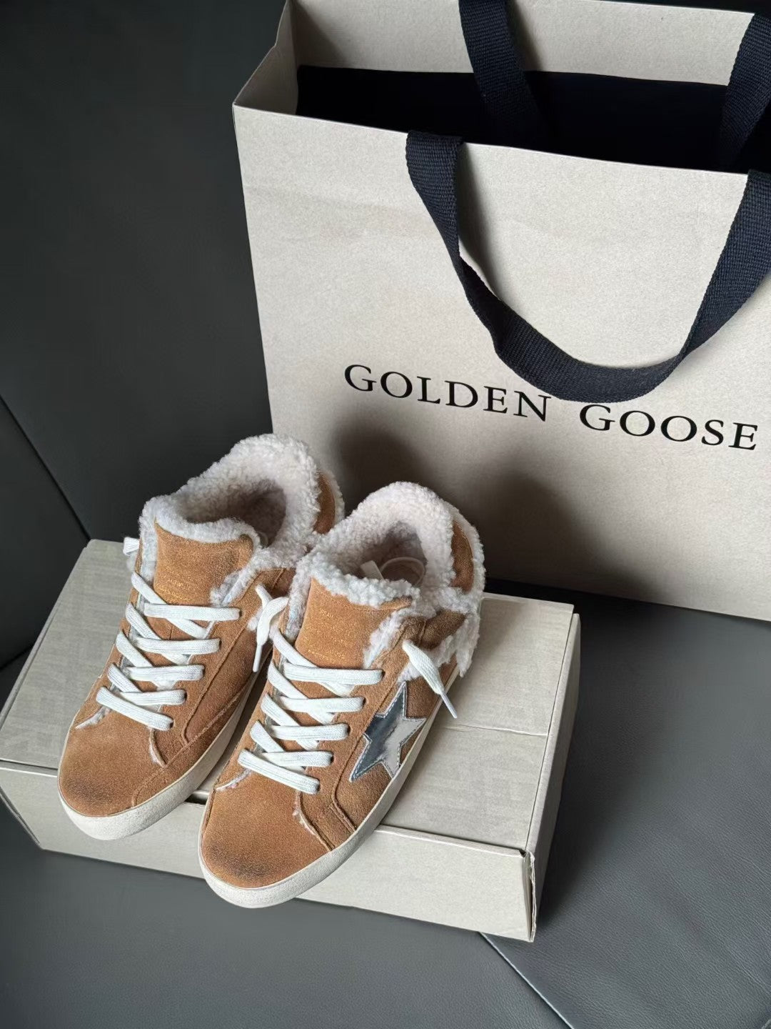 Brown suede high-top sneakers with white shearling collar and blue star patch, lace-up design.