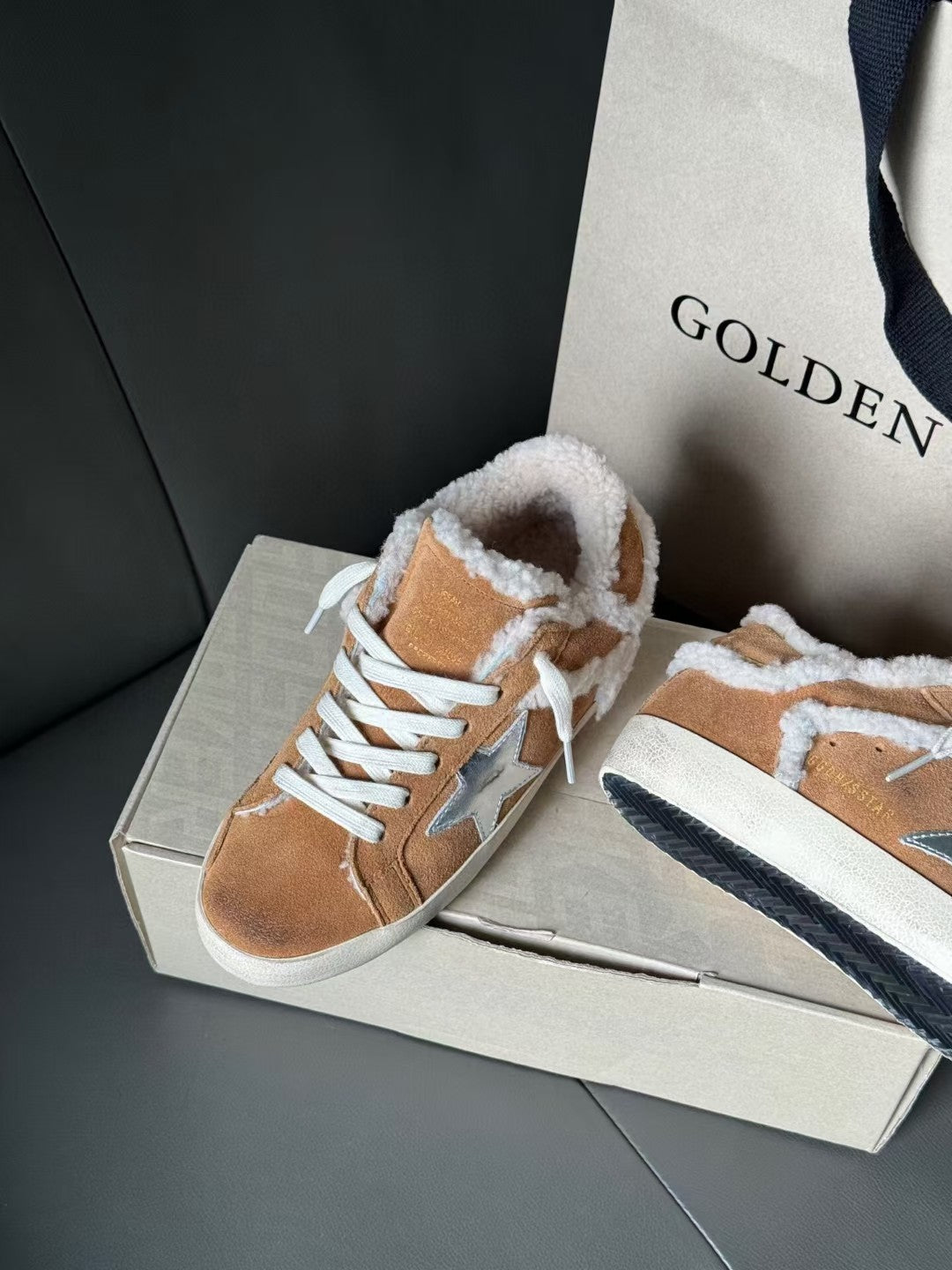 Brown suede high-top sneakers with white shearling lining, blue star detail, and white laces.