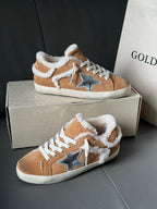 Brown suede high-top sneakers with white shearling trim, blue star patches, and white laces.