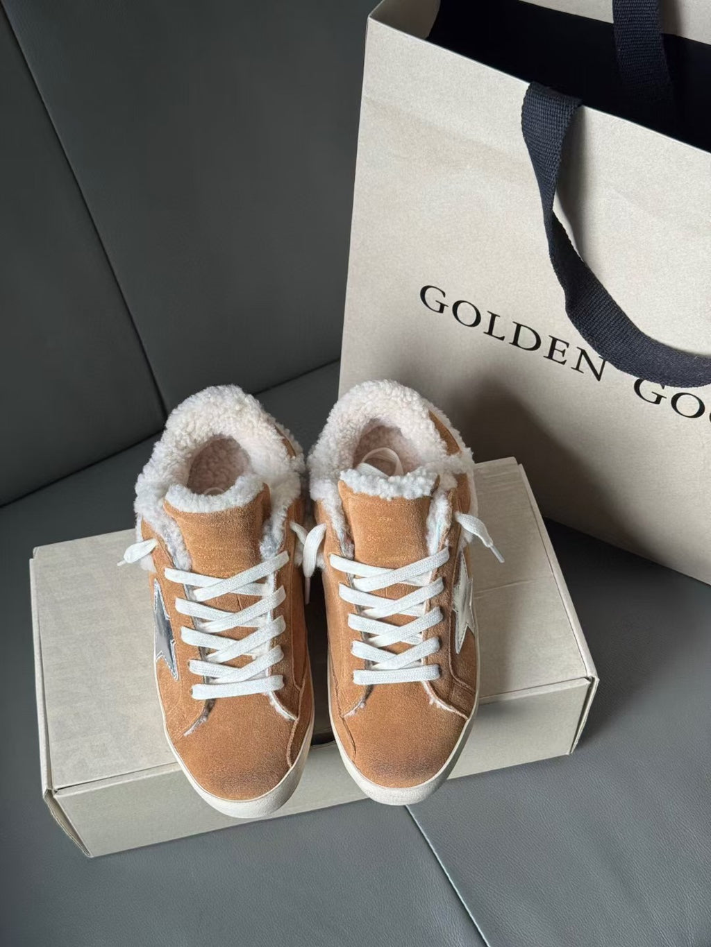 Brown suede high-top sneakers with white shearling trim and blue star logo, shown side by side.