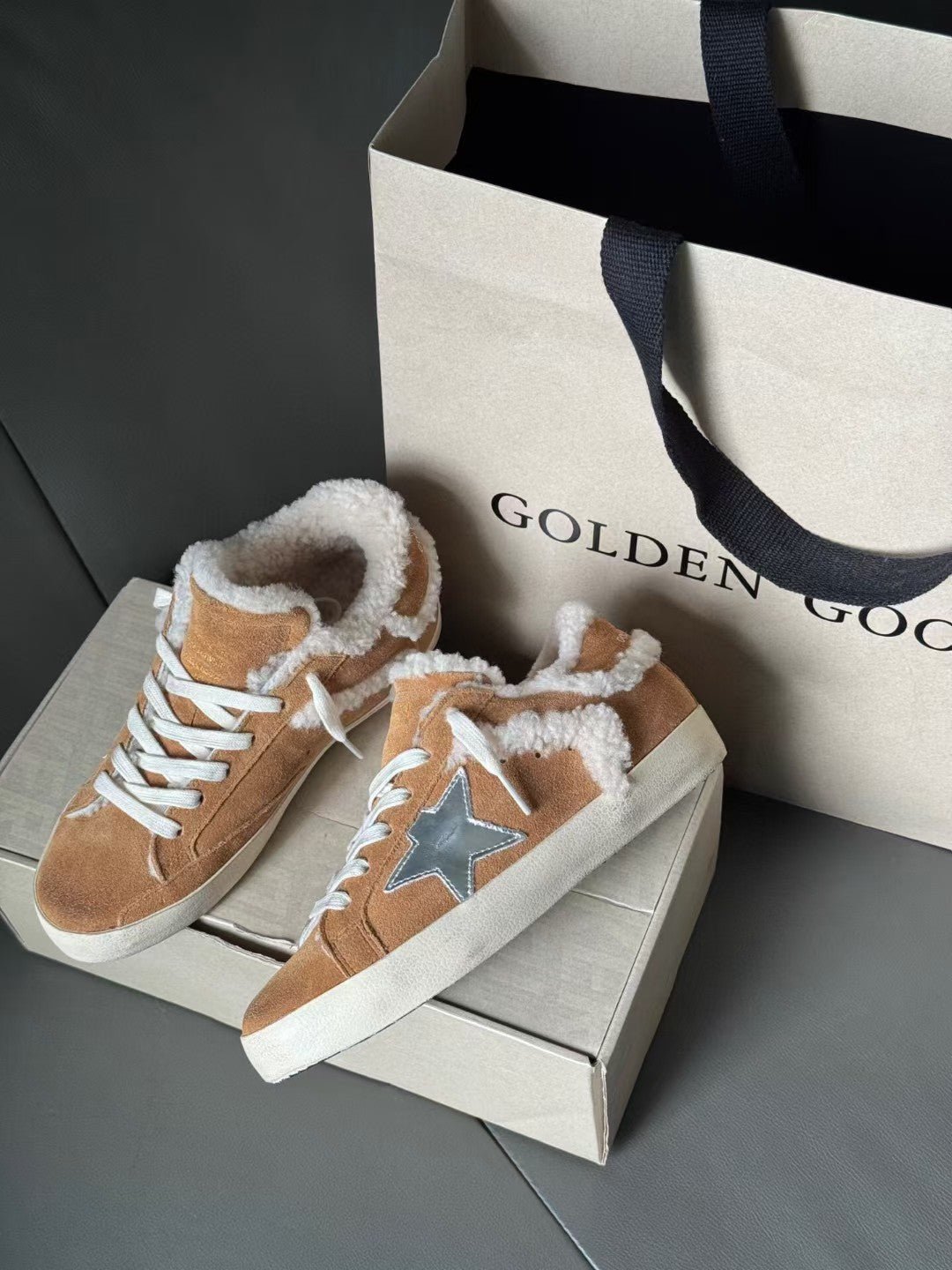 Brown suede high-top sneakers with white shearling collar and blue star patch, lace-up style.