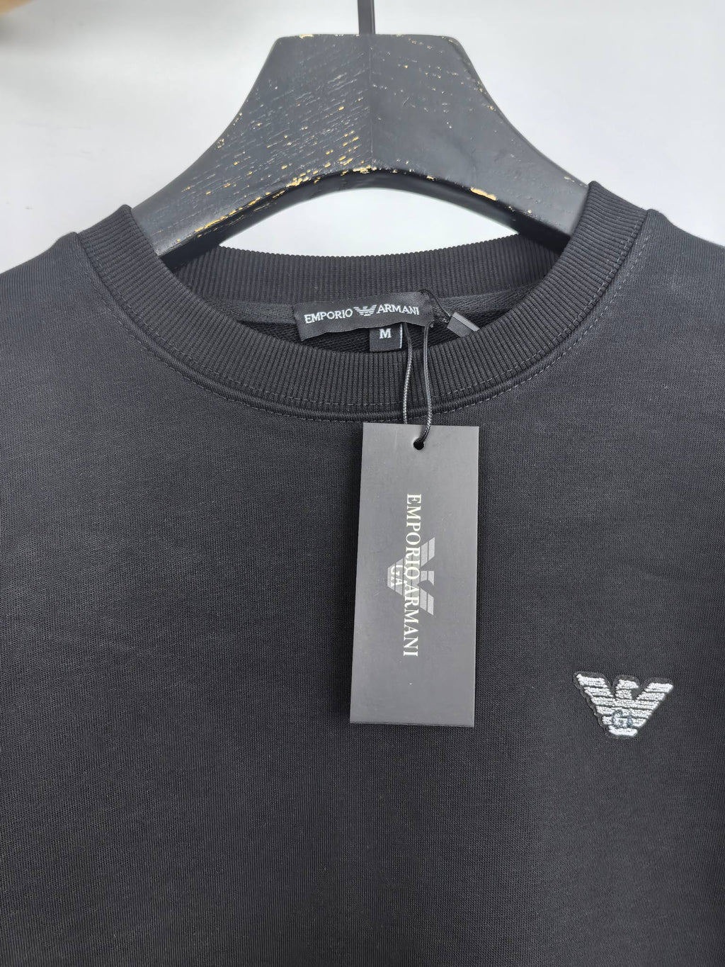 Dark gray crewneck sweatshirt with chest logo and neck tag
