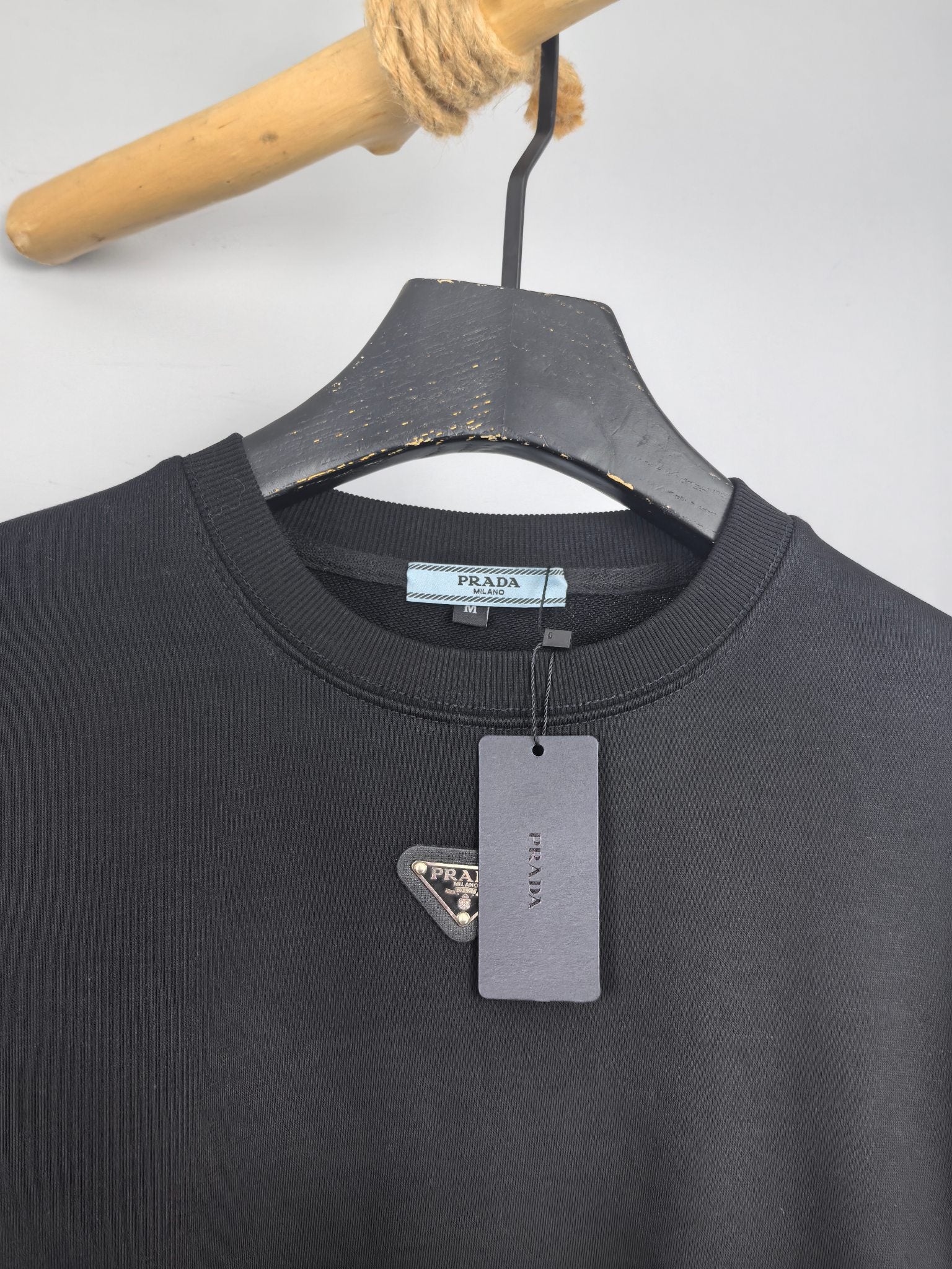 Dark gray sweatshirt neckline with Prada triangle logo patch and size tag