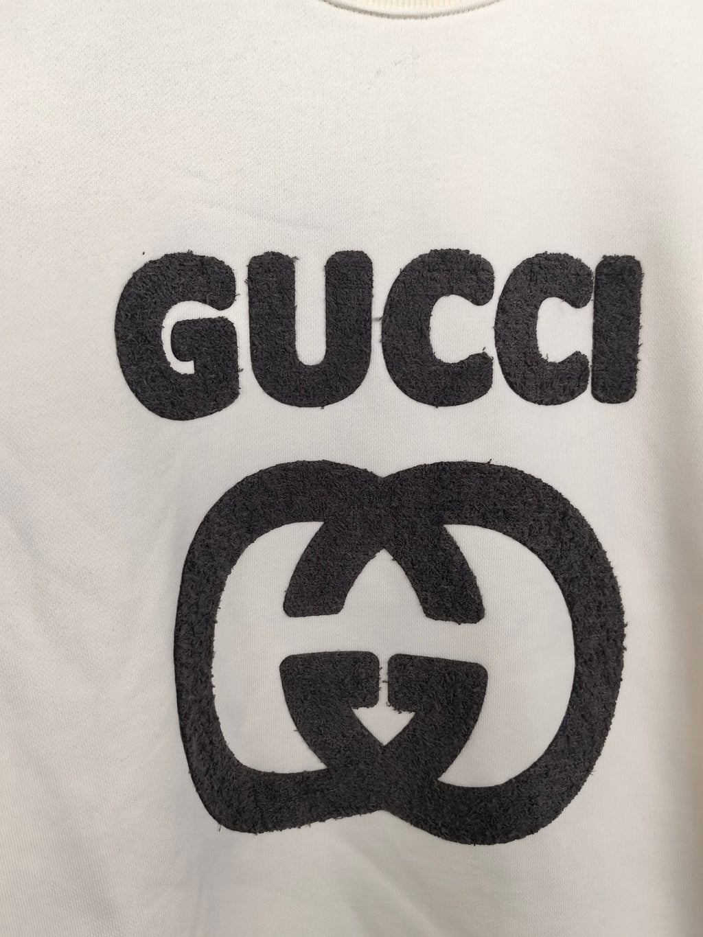 Cream sweatshirt front with large black GUCCI and GG emblem graphic