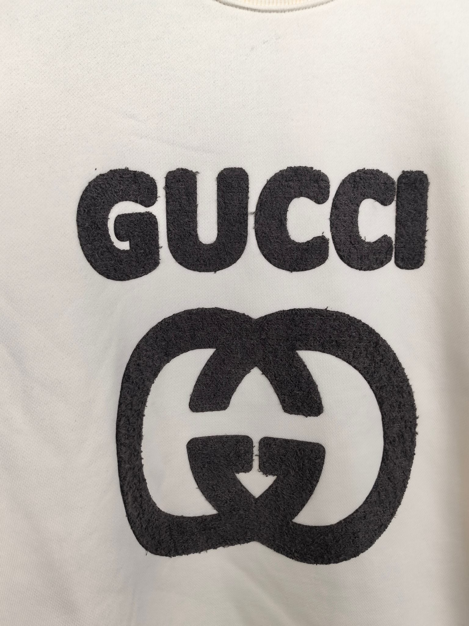 Cream sweatshirt front with large black GUCCI and GG emblem graphic