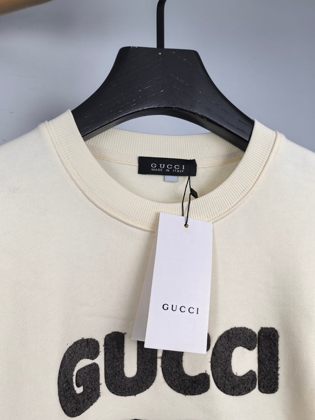 Cream crewneck sweatshirt with Gucci logo tag at neckline