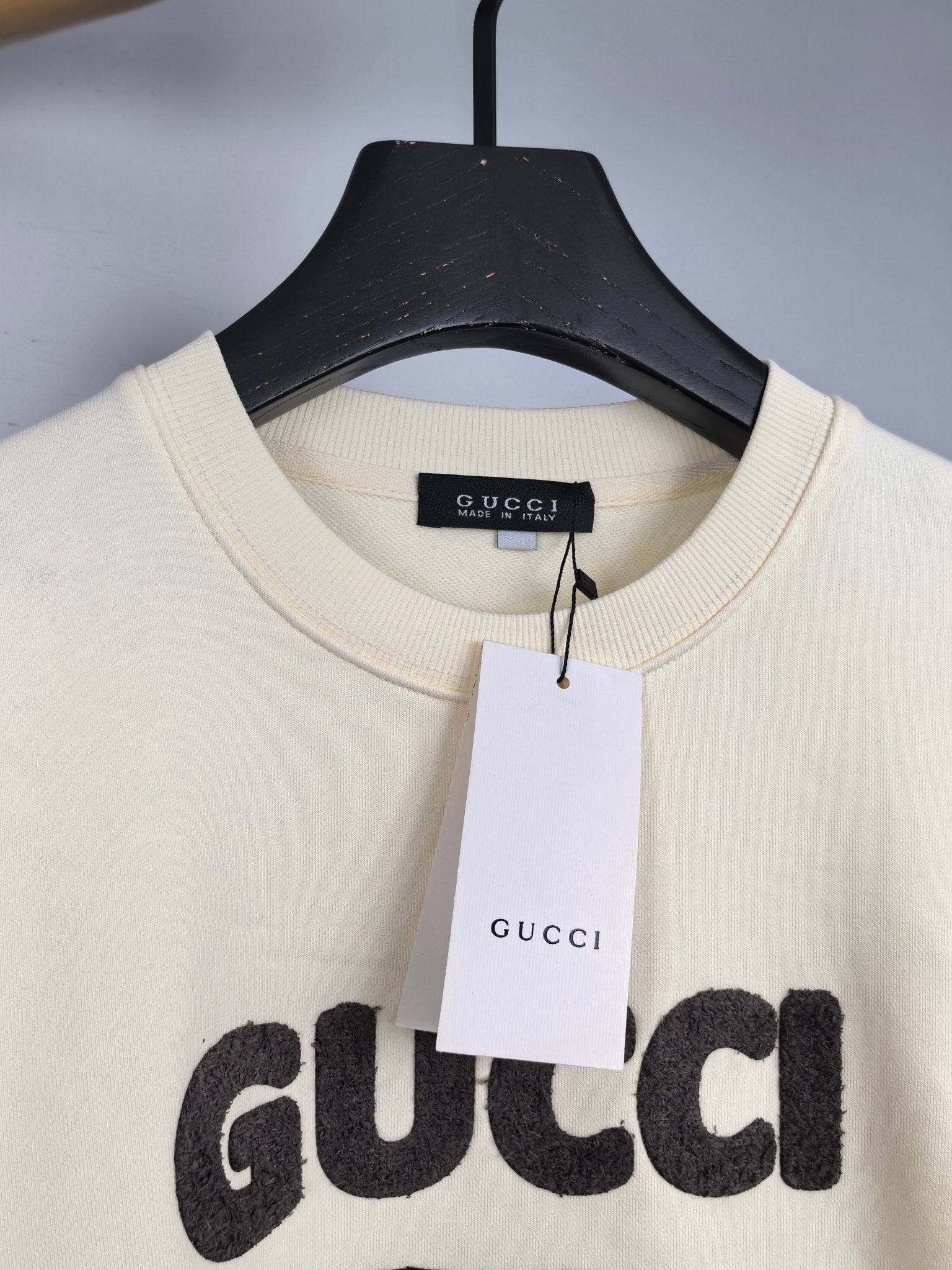 Cream crewneck sweatshirt with Gucci logo tag at neckline