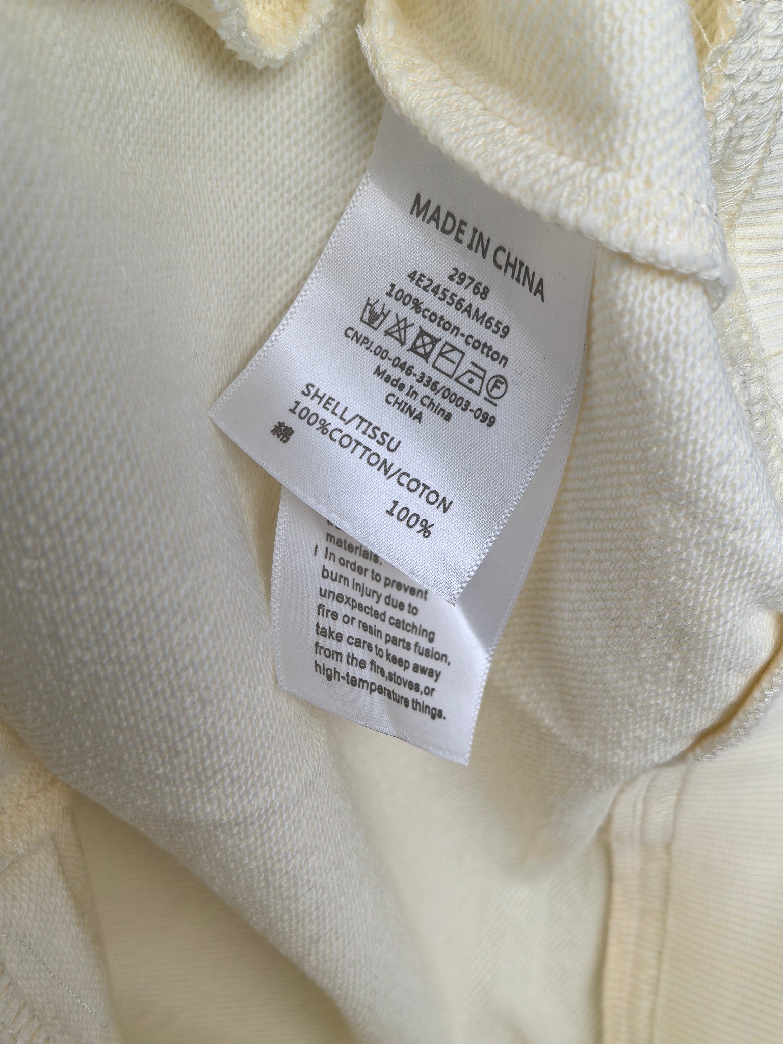 Cream sweatshirt neck tag showing Made in China and 100% cotton