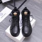 Black lace-up high-top shoes with gold emblem on the tongue and padded collars