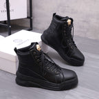 Pair of black lace-up high-top boots with gold emblem details and thick tread soles