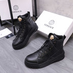 Black lace-up high-top boots with gold emblem on tongue and platform-style tread sole