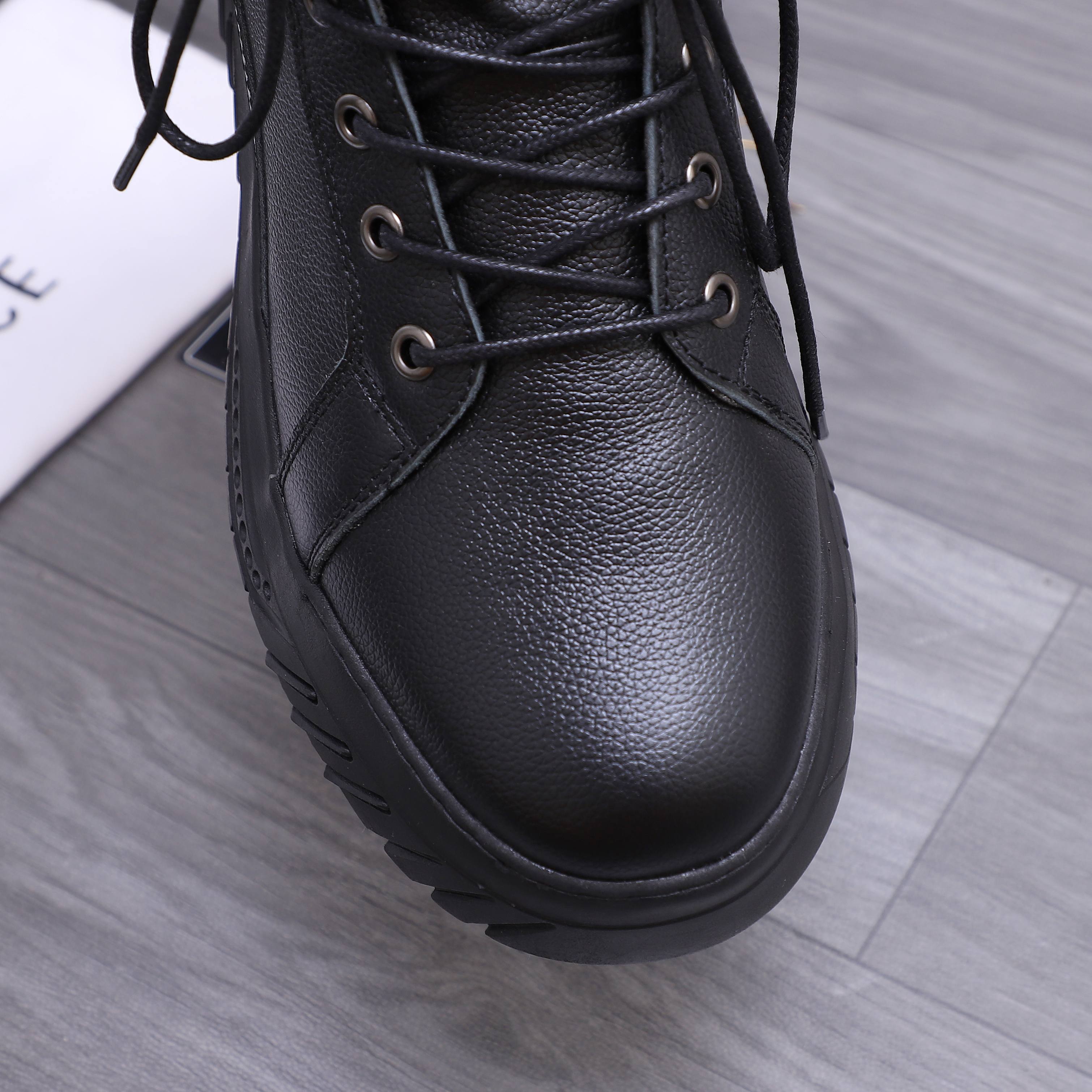 Close-up of black leather lace-up high-top shoe upper with metal eyelets