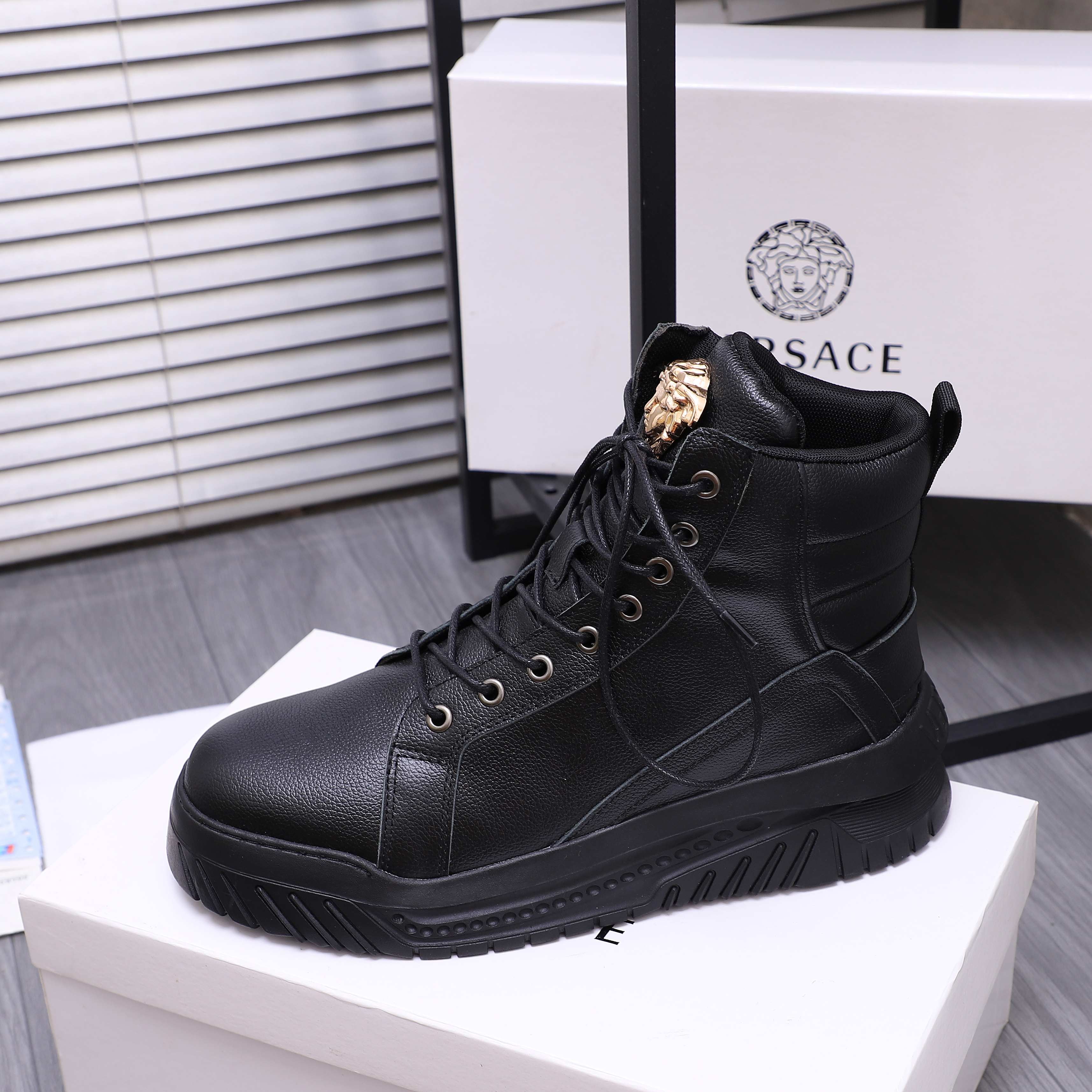 Black lace-up high-top sneaker boots with gold emblem on tongue and textured outsole