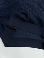Dark blue hoodie hem with ribbed band and monogram texture, close-up.