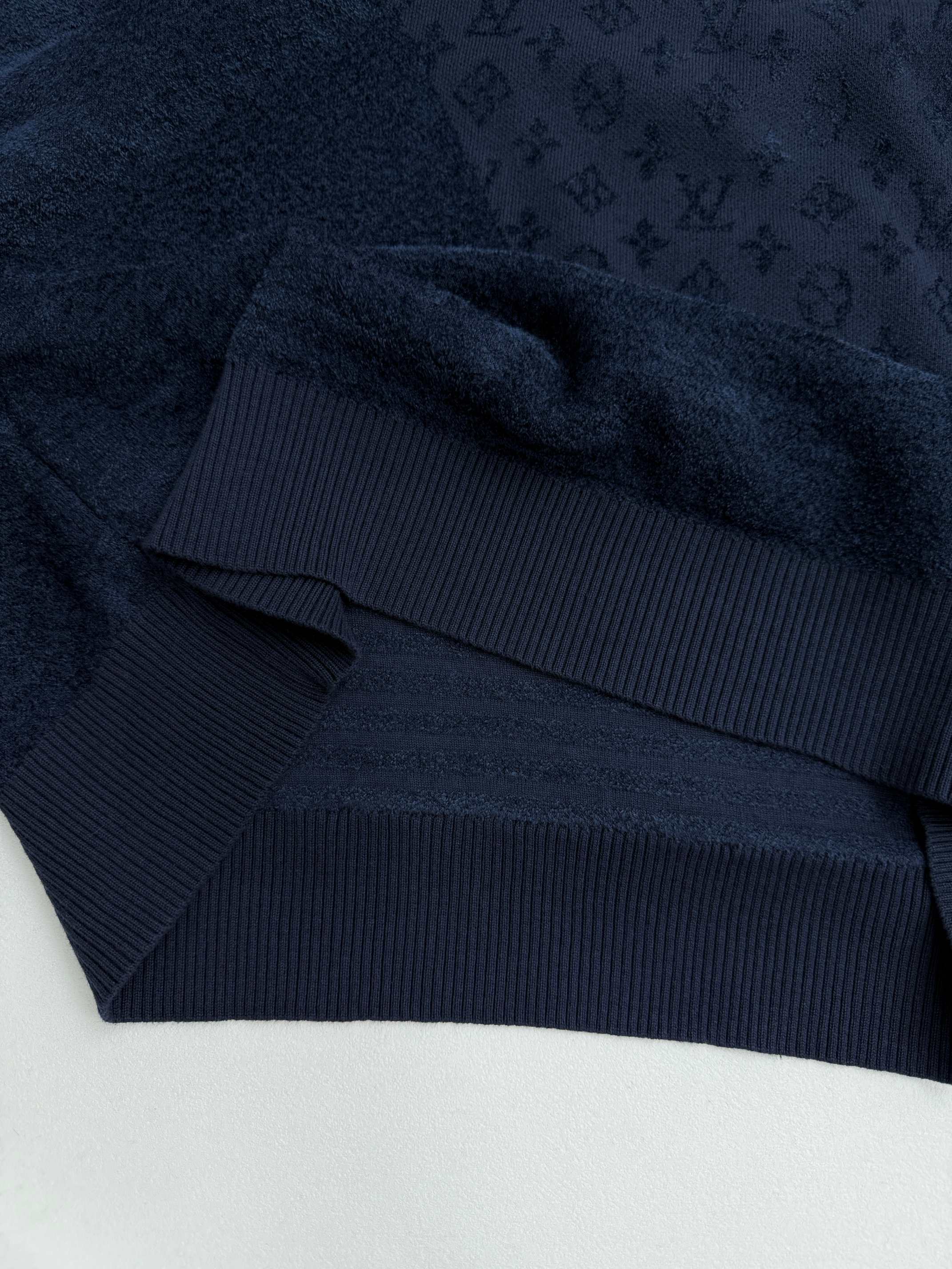 Dark blue hoodie hem with ribbed band and monogram texture, close-up.