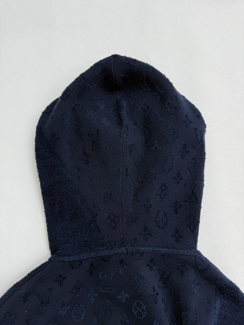 Dark blue monogram hood with front seam, close-up.