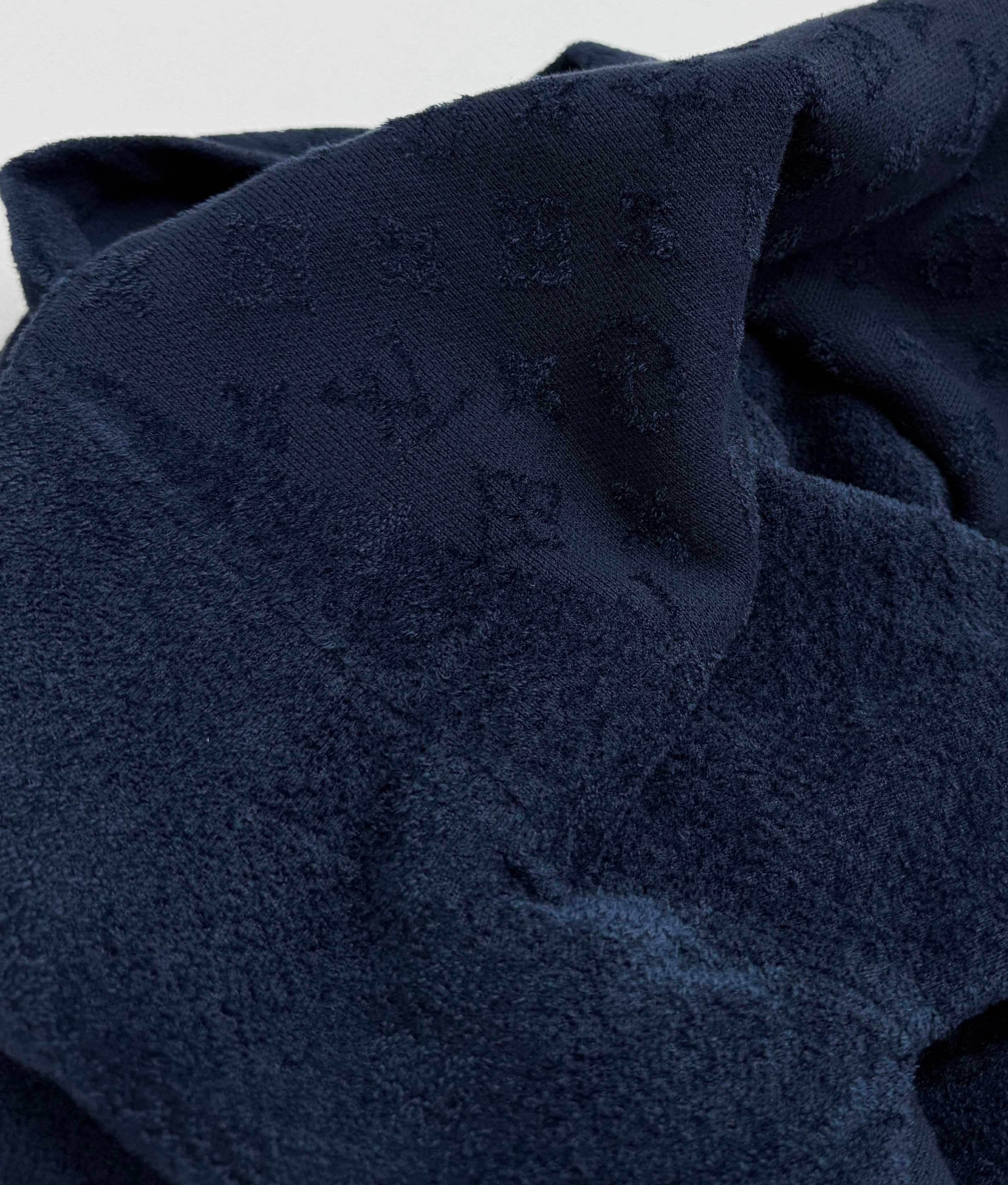 Dark blue monogram fabric with hood fold, close-up.