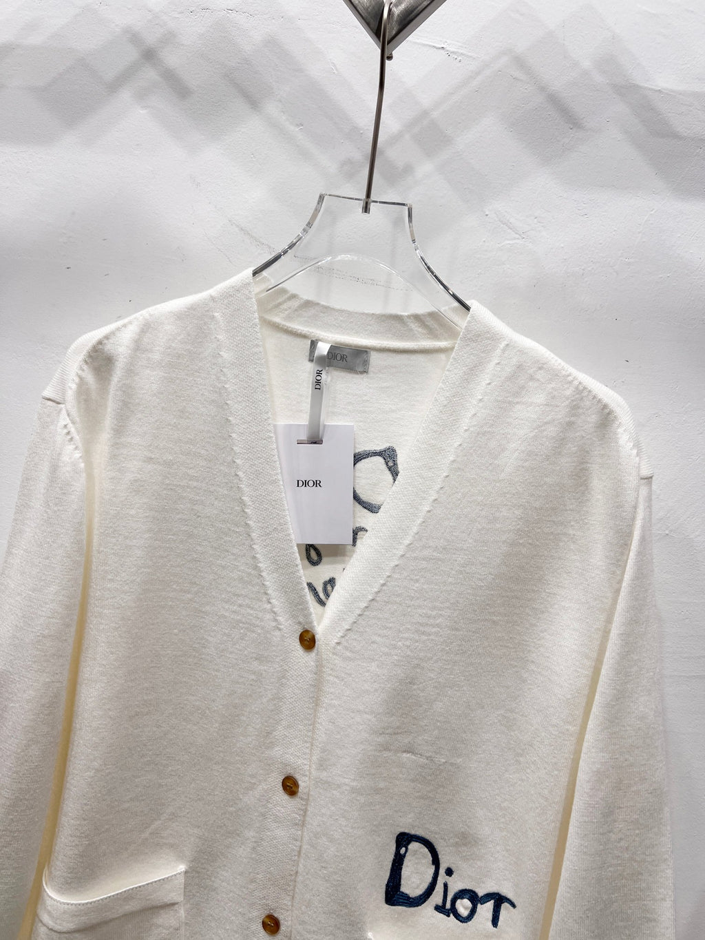 Dior white cardigan close-up of V-neck placket and button front with Dior logo