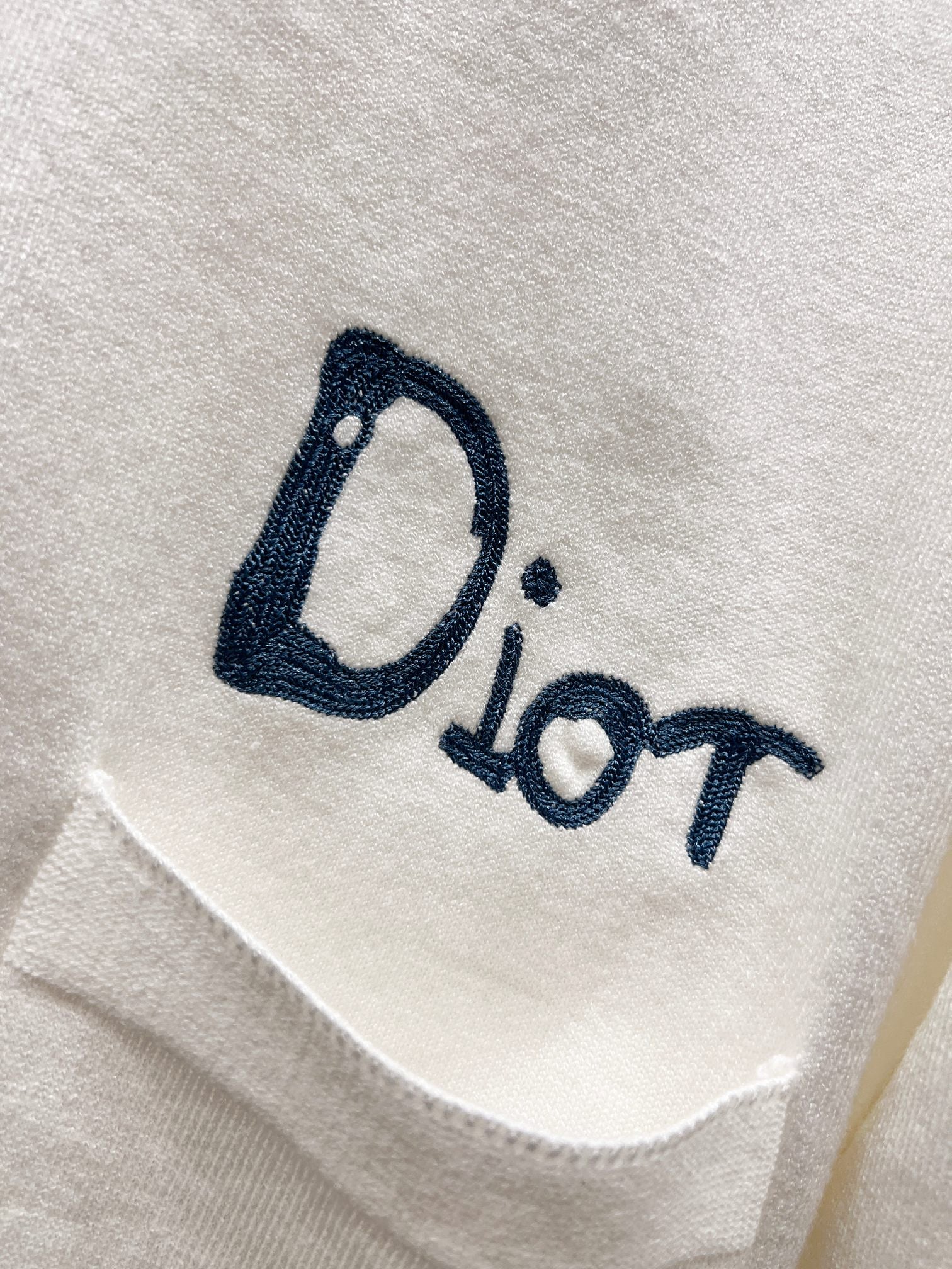 Dior white cardigan front pocket area with blue 'Dior' logo