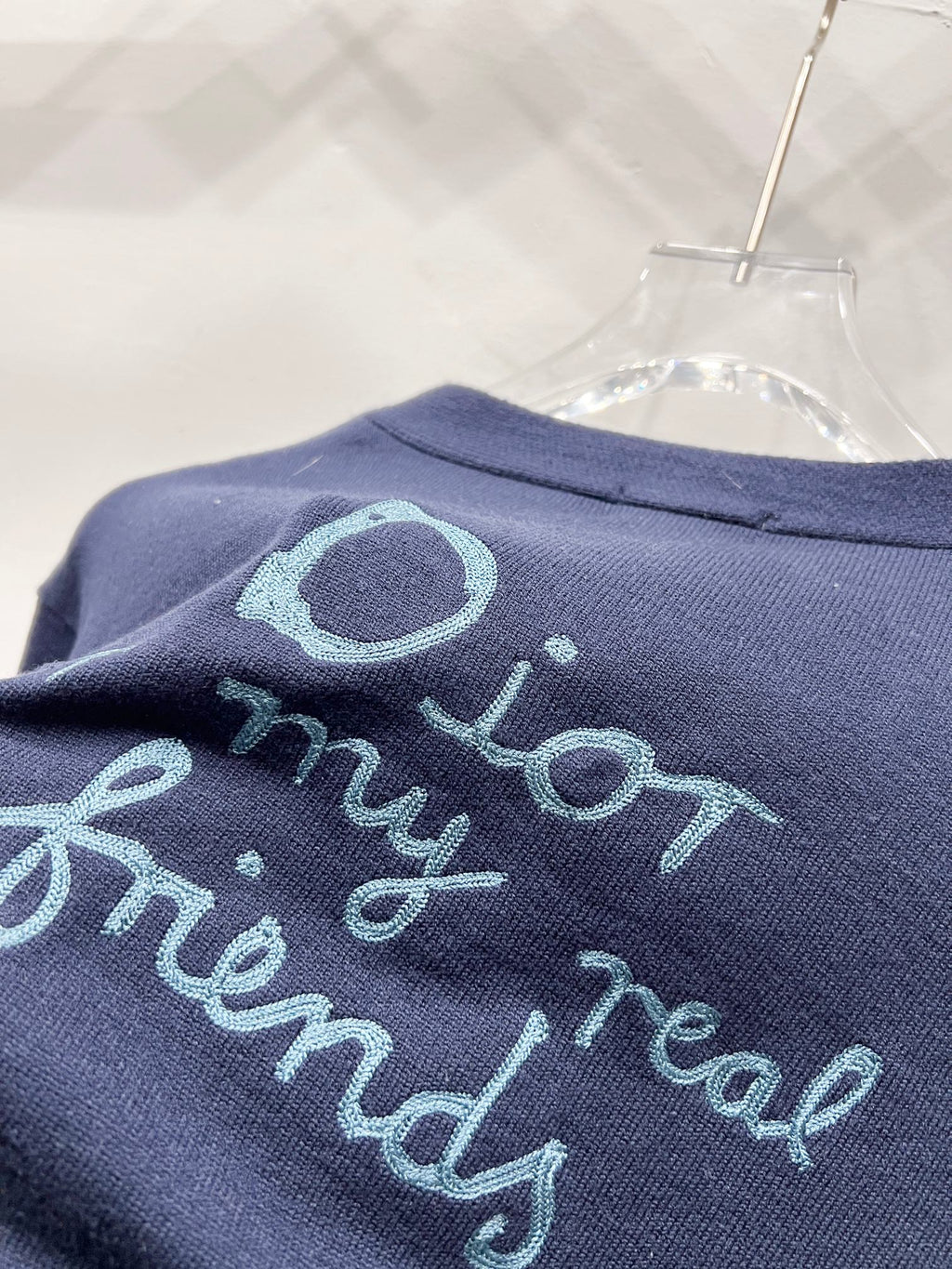Navy fabric close-up with turquoise embroidered lettering and oval graphic