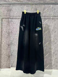 Black wide-leg pants with elastic waist and white embroidered logo on the legs