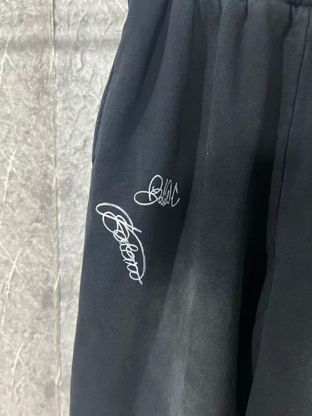 Black pants with white script embroidery on the side