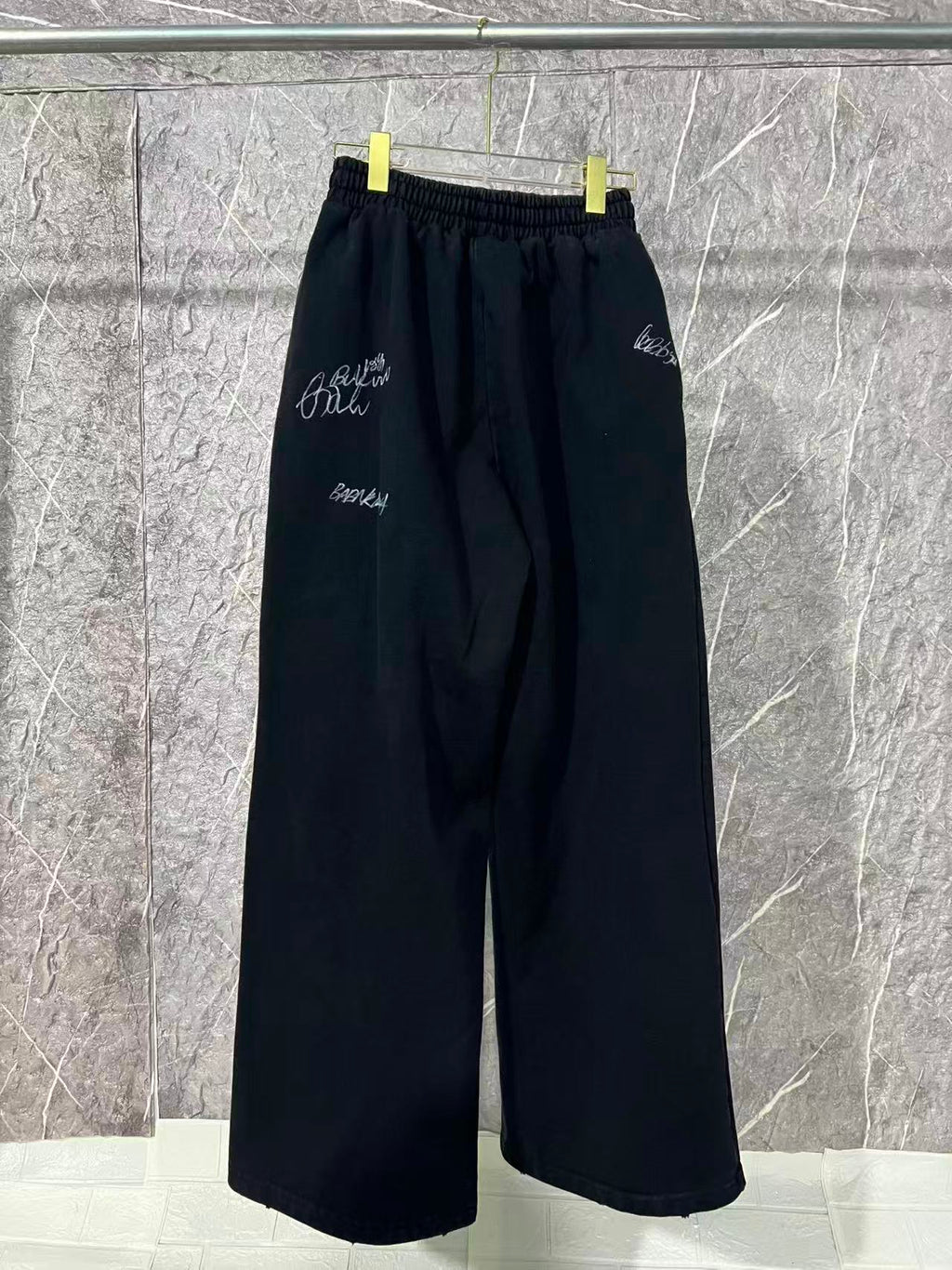 Black wide-leg pants with elastic waist and small white embroidered marks