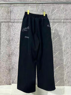 Black wide-leg pants with elastic waist and small white embroidered marks
