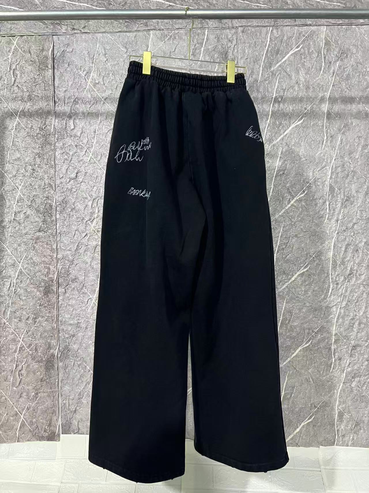 Black wide-leg pants with elastic waist and small white embroidered marks