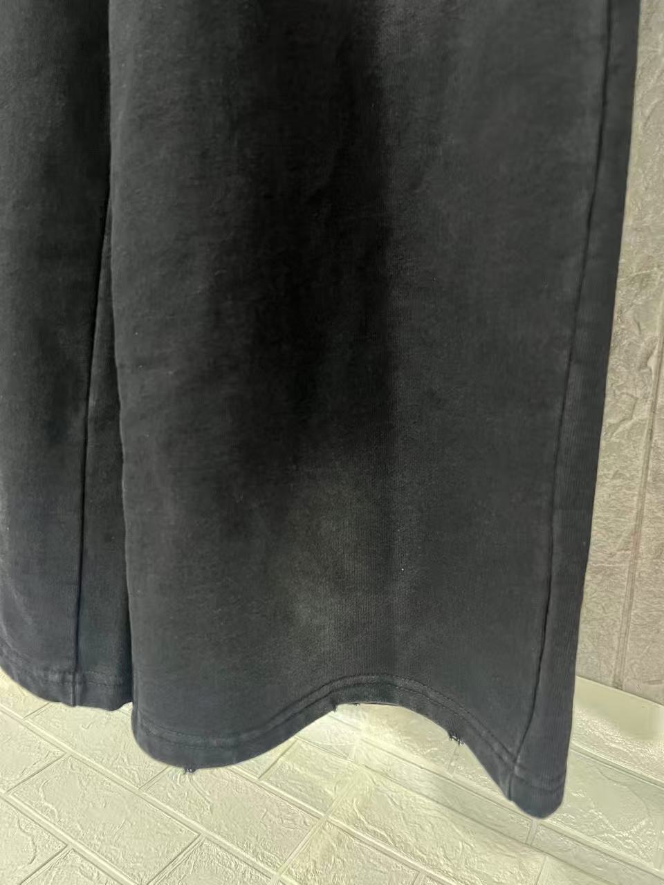 Black wide-leg pants hem detail with smooth fabric finish