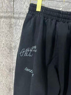 Black pants side view with elastic waist and white script logo embroidery