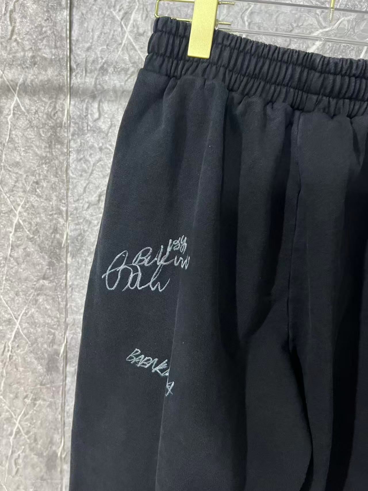 Black pants side view with elastic waist and white script logo embroidery
