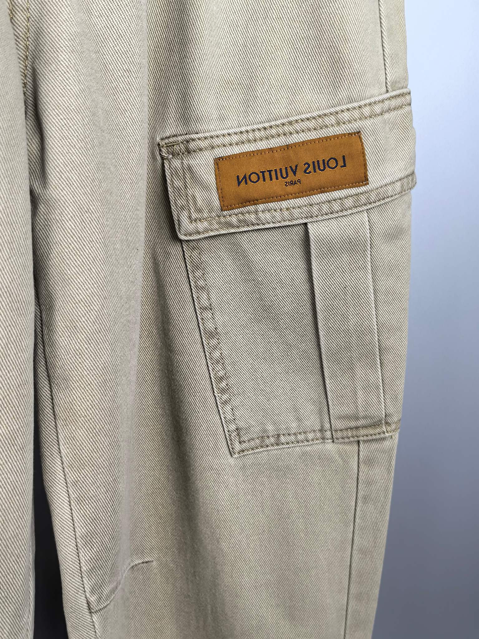 Beige denim pants with stitched pocket seams and tan branded patch