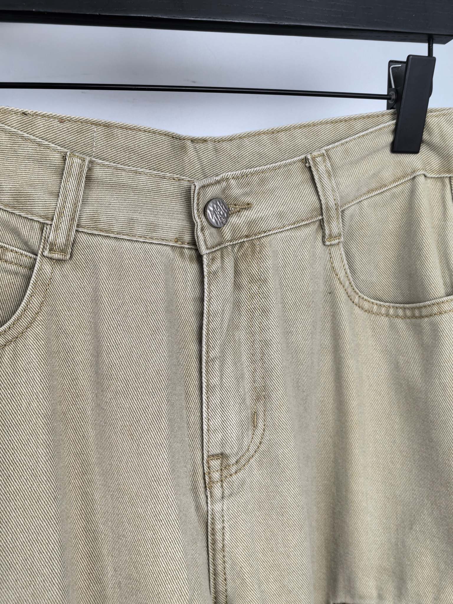 Beige denim pants close-up of waistband seams and front metal button