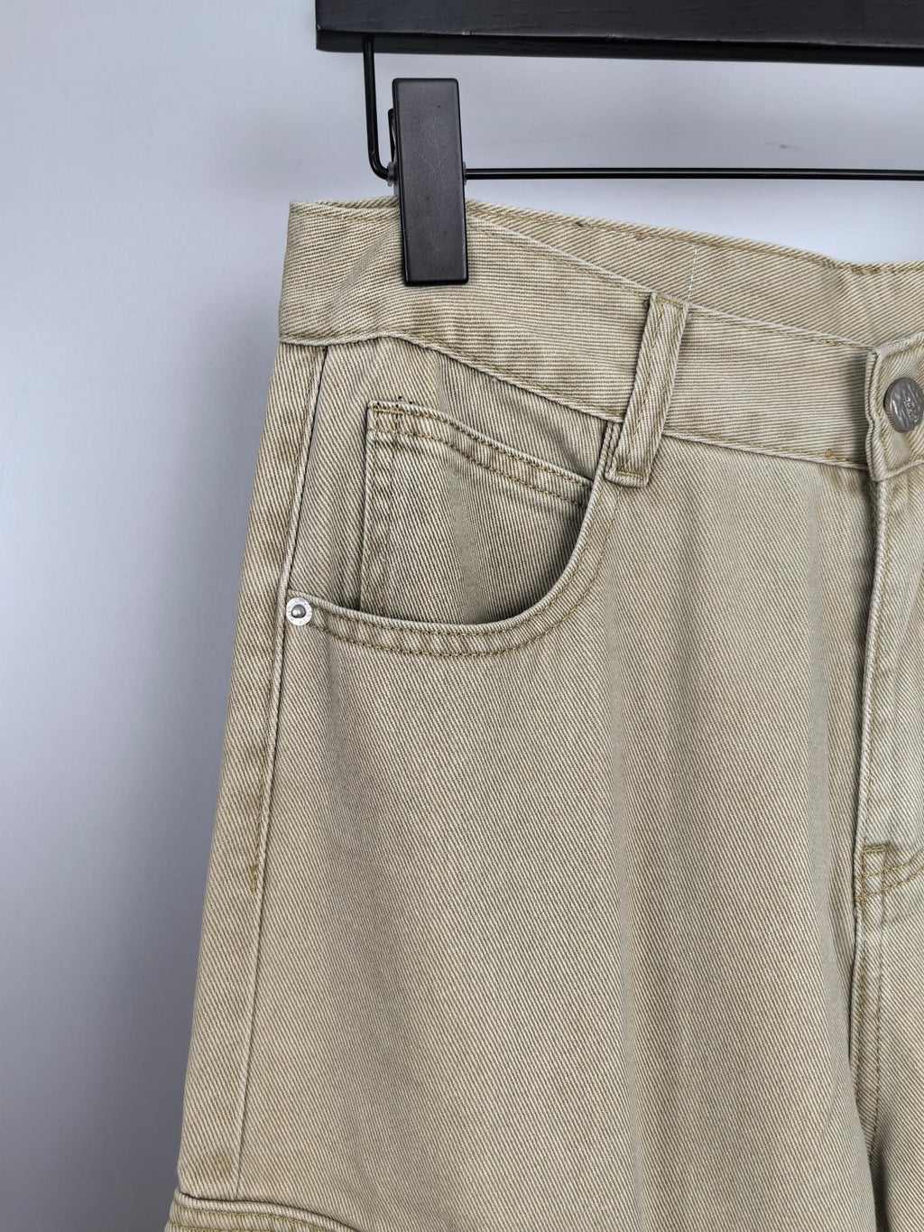 Beige denim pants close-up of curved side pocket and belt loop tab