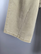 Beige denim pants leg with visible side seam and hem stitching