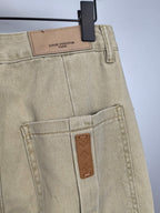 Beige denim pants close-up of waistband label and tan leather pocket tag
