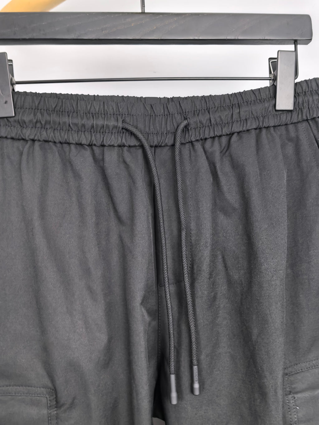 Dark elastic-waist cargo pants with drawstring and two metal aglets.