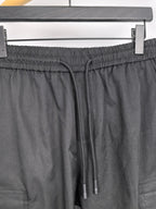 Dark elastic-waist cargo pants with drawstring and two metal aglets.