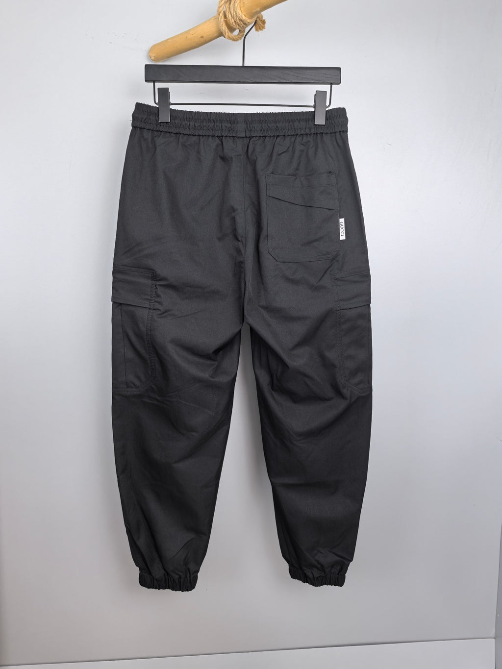 Dark cargo pants with elastic waist and roomy legs, side pockets, and small logo tag.