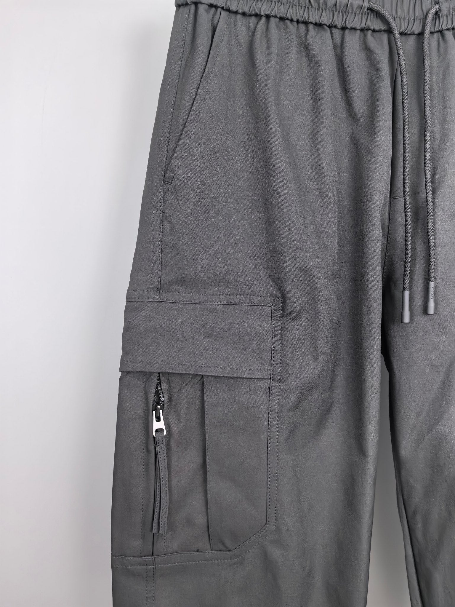 Dark cargo pants with elastic waist, drawstring, and front pocket panels.