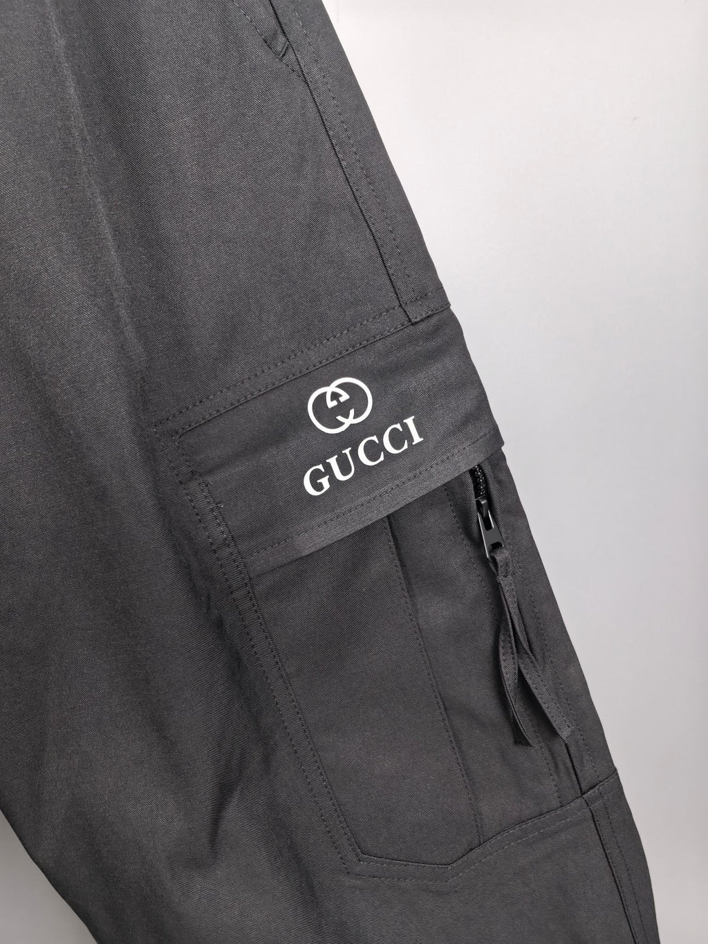 Dark cargo pants with stitched side pocket and GUCCI logo patch.