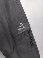 Dark cargo pants with stitched side pocket and GUCCI logo patch.