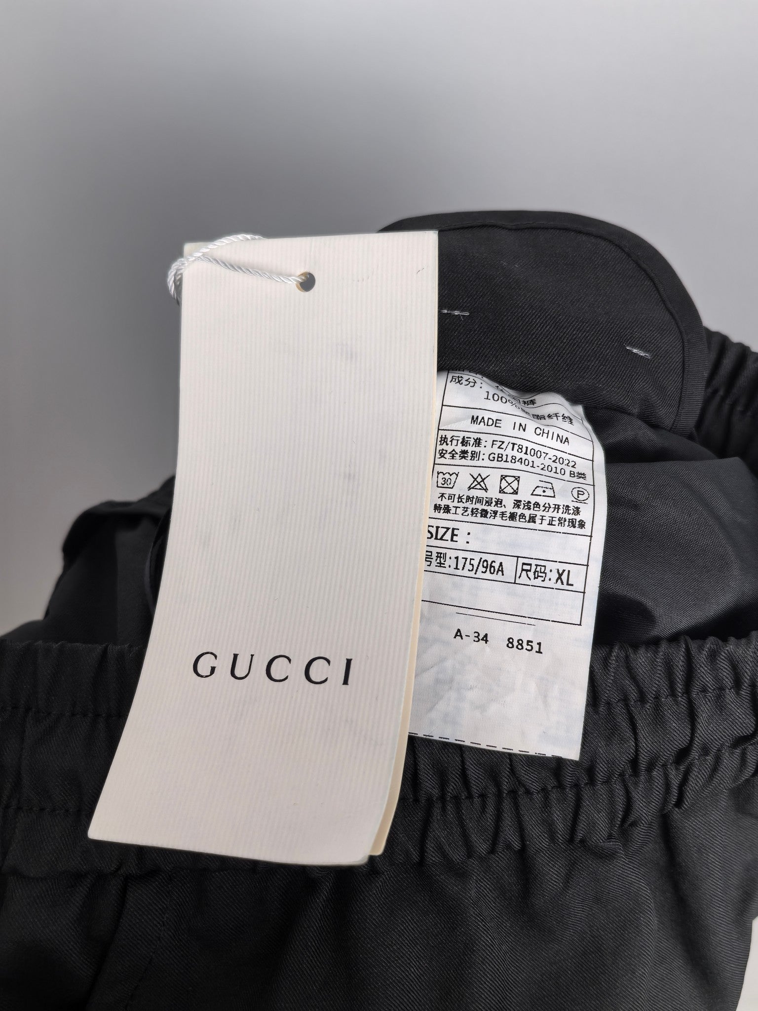 Black cargo pants with paper tag showing GUCCI text and size label.