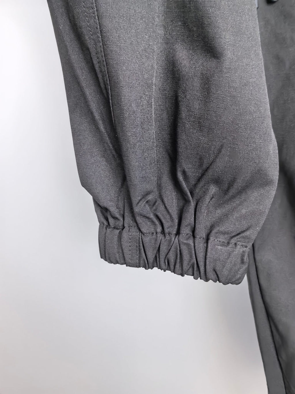 Dark cuffed cargo pants with gathered elastic hem at ankle.